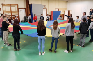 des enfants tiennent un tous ensemble un grand tissus rond multicolores